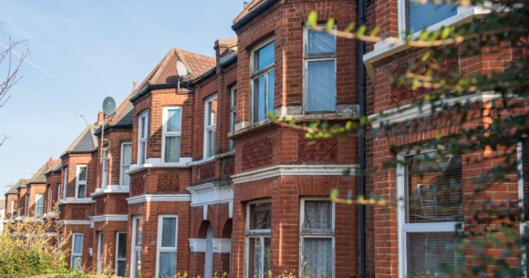 A row of red brick-finished houses with white casement windows