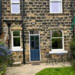 Back of a house in Ilkley with a blue timber back door sliding sash windows and garden furniture